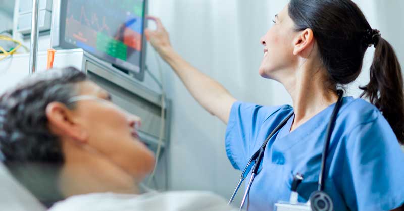 nurse looking at monitor above patient's bed